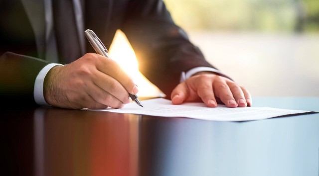 Person signing paper on desk