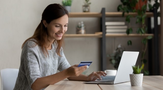 Woman on computer holding debit card