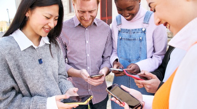 group of people gathered in a circle looking at their phones