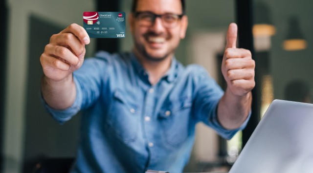 man holding a NEBAT checkcard in front of him and giving a thumbs up